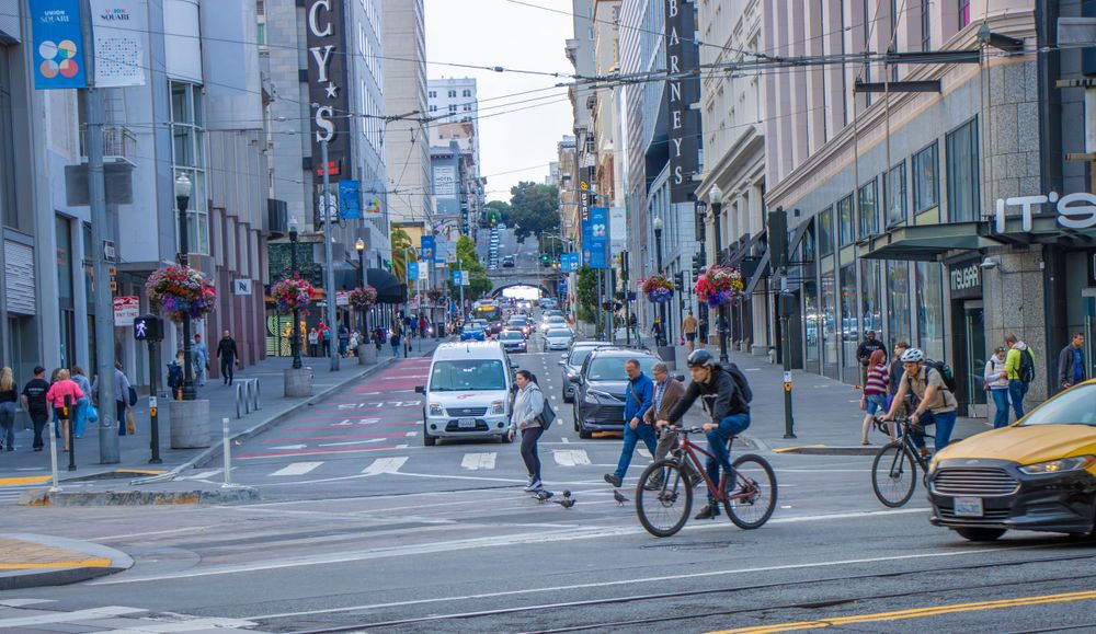 Cyclists and pedestrians sharing the road with cars on a busy San Francisco street.