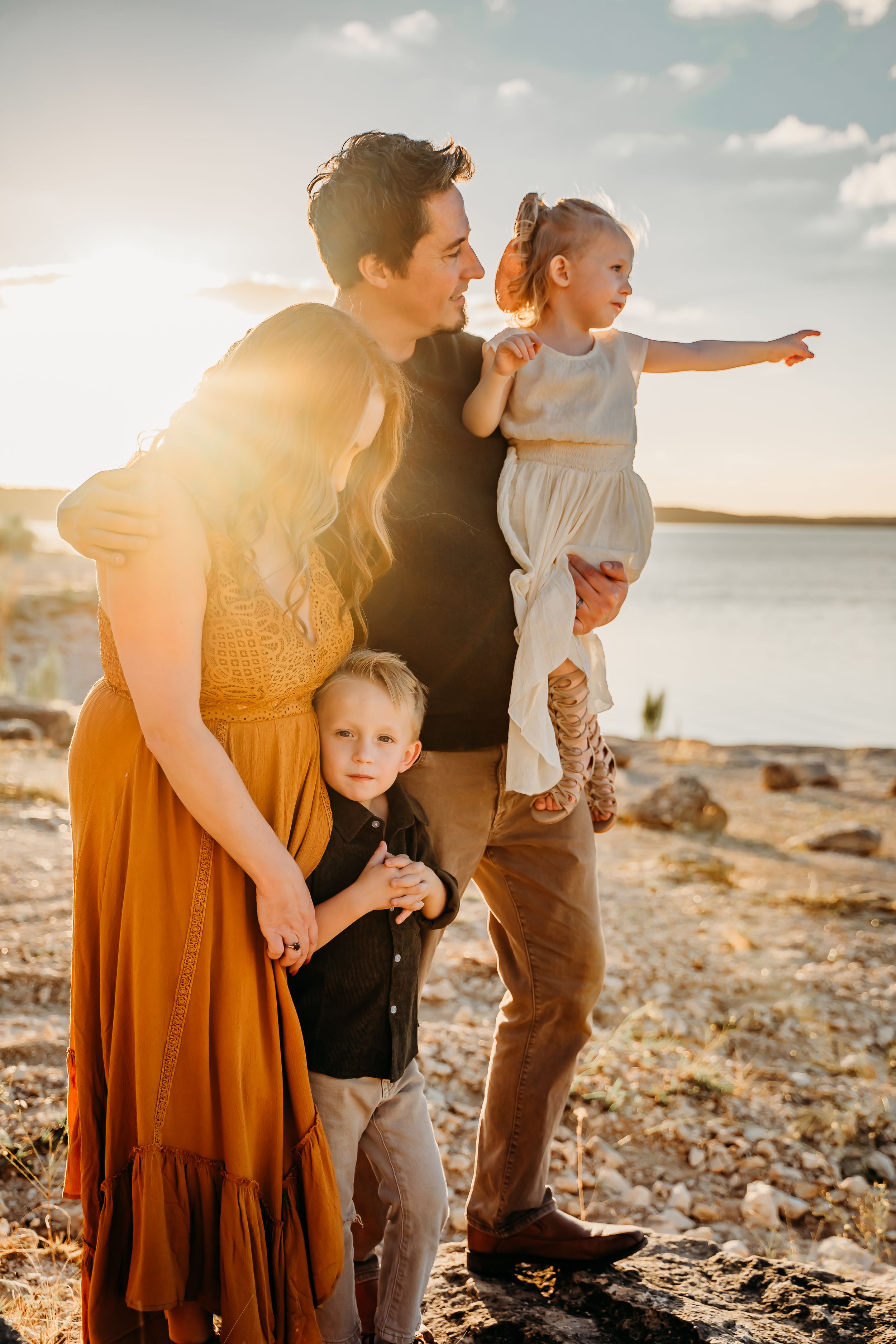 Family enjoying sunset moment together on rocky beach.
