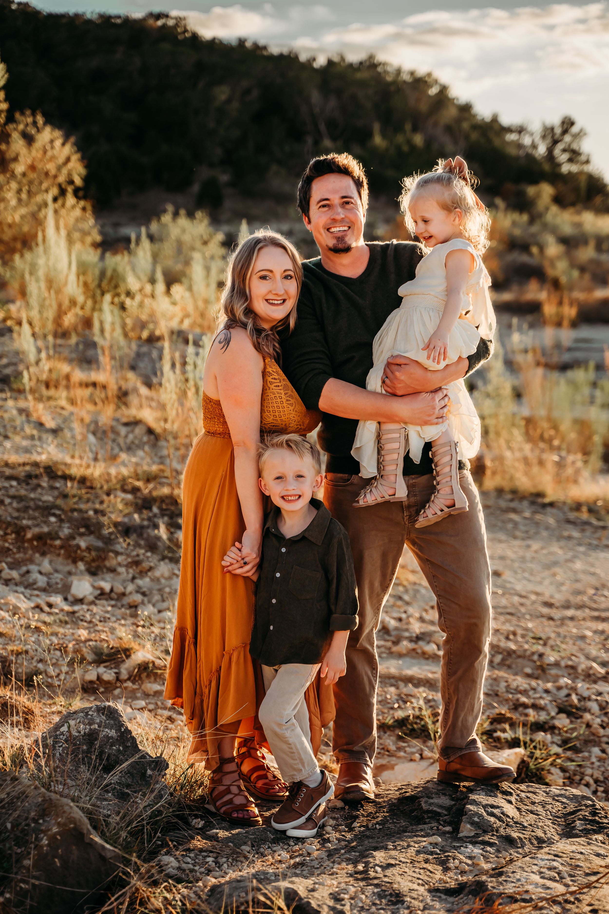 Family portrait in golden lighting with desert brush and mountains in background.