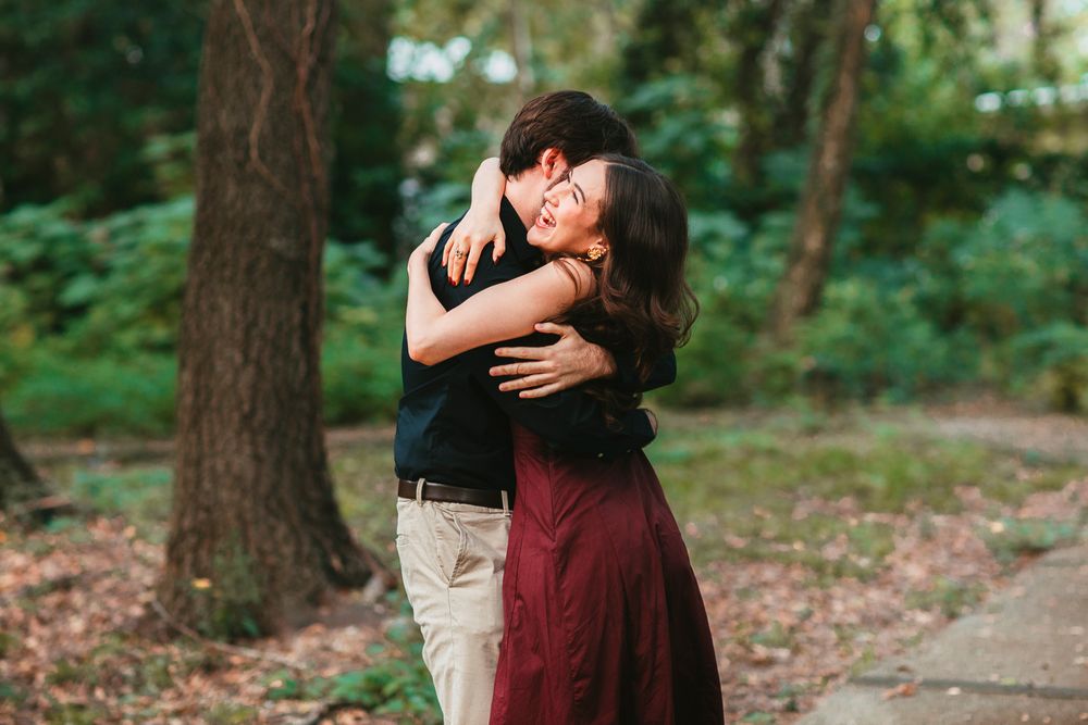 A romantic couple embraces on a wooded path during an outdoor photo session in a forest setting.