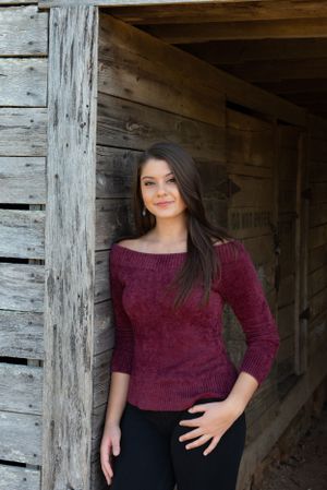 Professional photoshoot featuring burgundy sweater and dark pants against rustic wooden backdrop.