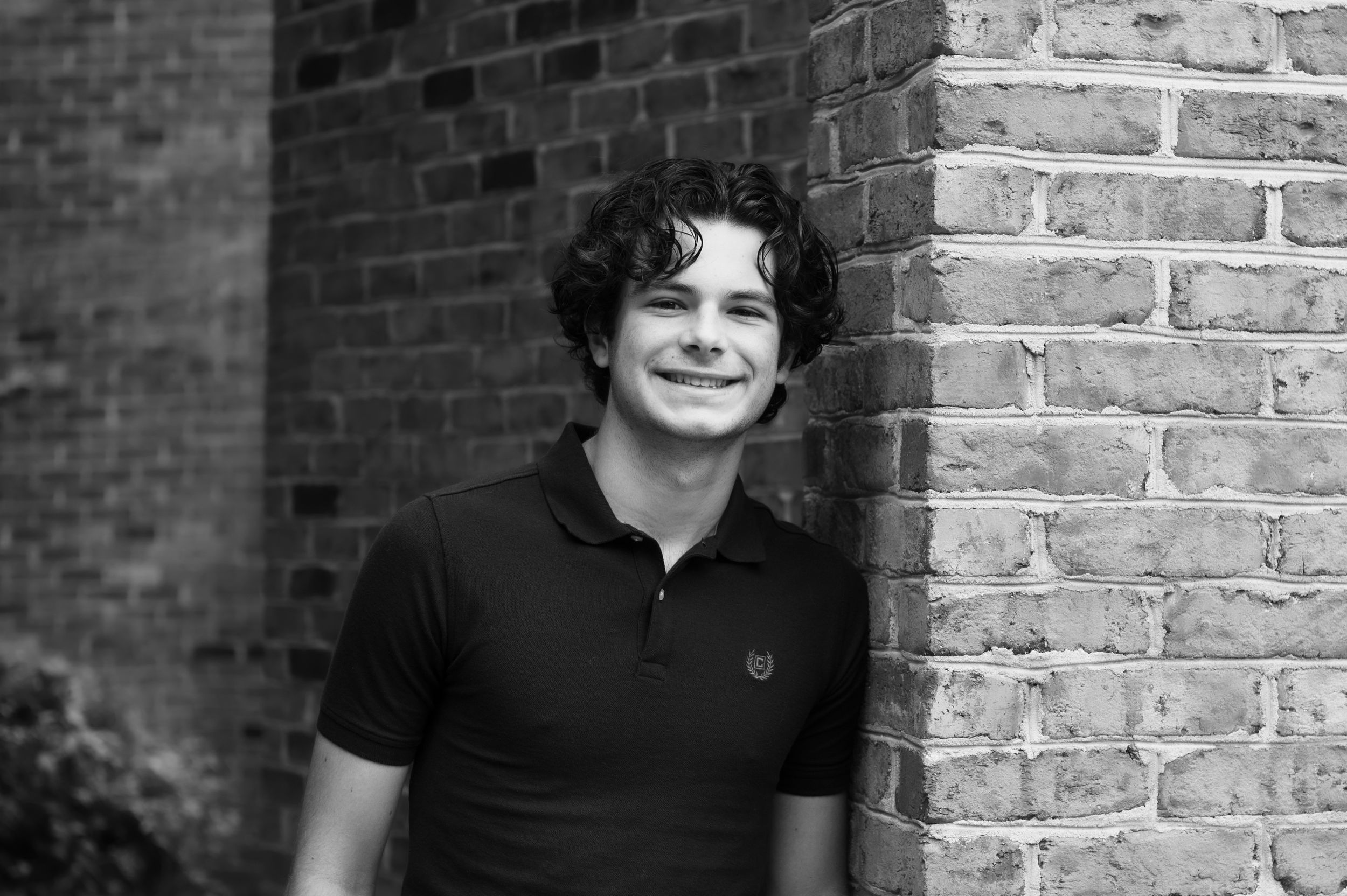 Portrait series against textured brick wall backdrop in natural lighting.