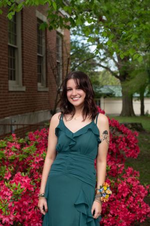 A joyful portrait by a brick building with vibrant pink azalea flowers in bloom.