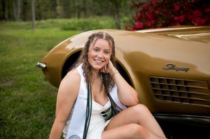 A gold vintage sports car photographed with a natural outdoor backdrop.