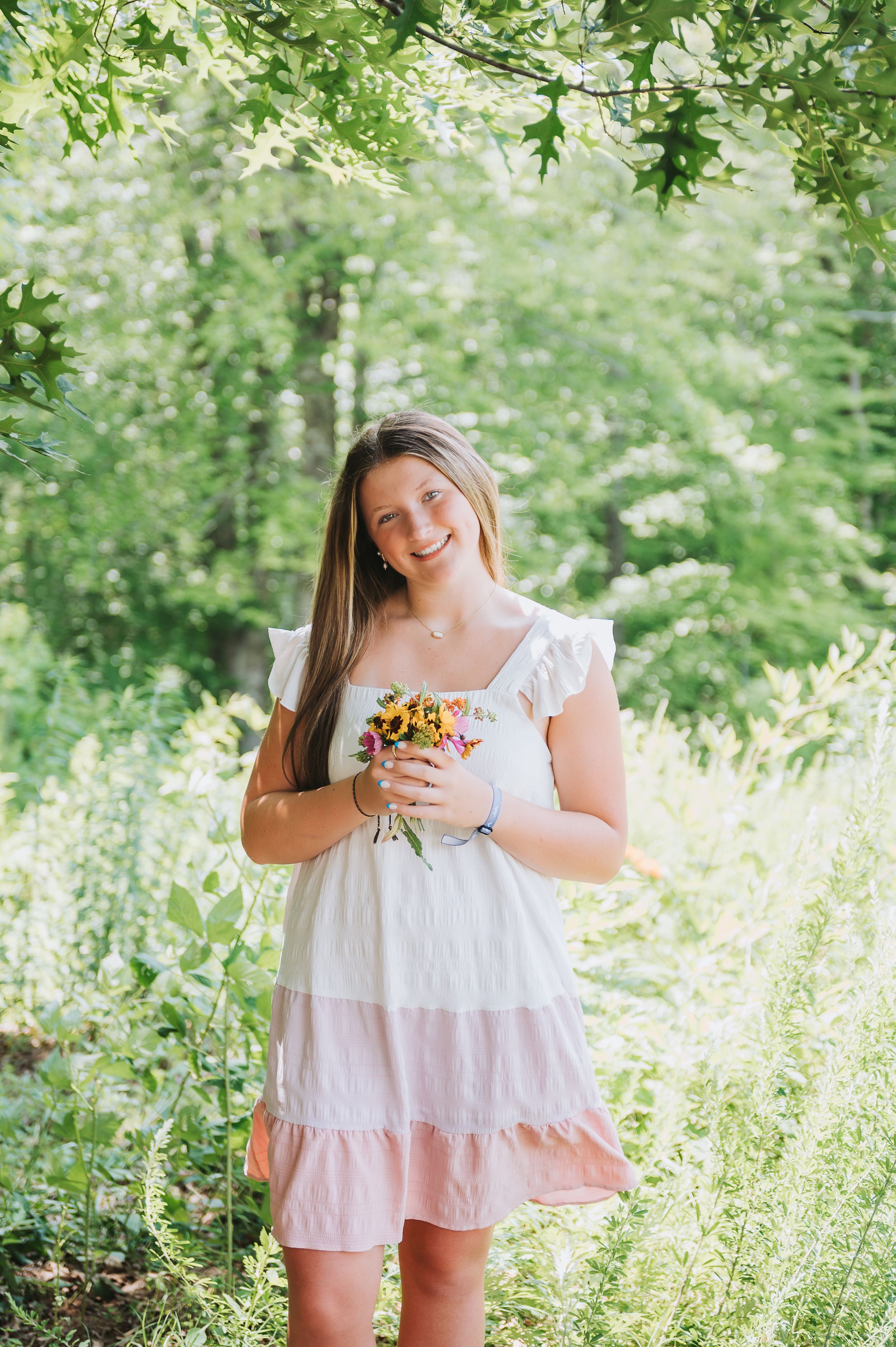 Summer portrait session in a sunlit garden with white dress and sunflowers.