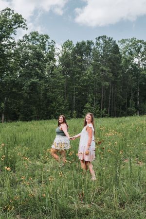Friends sharing laughter in a wildflower field on a beautiful summer day.