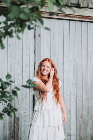 White wooden fence backdrop creates rustic atmosphere for outdoor portrait photography.