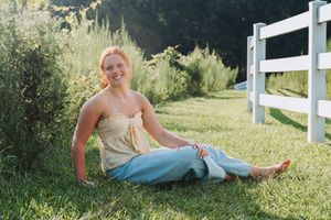 Sunny outdoor photo session by rustic white fence in grassy field.