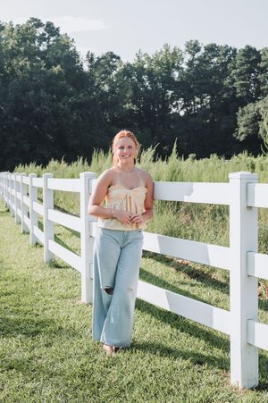 Lifestyle photography along white wooden fence in summertime meadow setting.