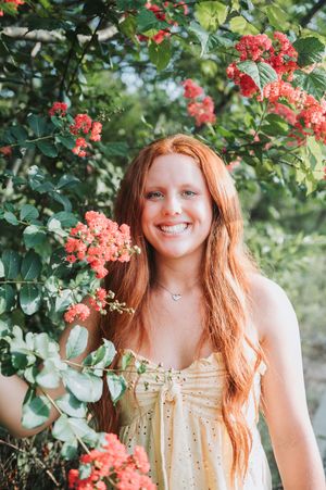 Romantic outdoor portrait surrounded by blooming coral flowers and greenery.