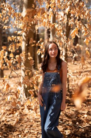 An autumn portrait surrounded by golden brown leaves and natural lighting.