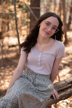 A natural light portrait on a fallen log in a wooded setting.