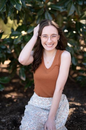 A cheerful outdoor portrait with magnolia leaves in the background.