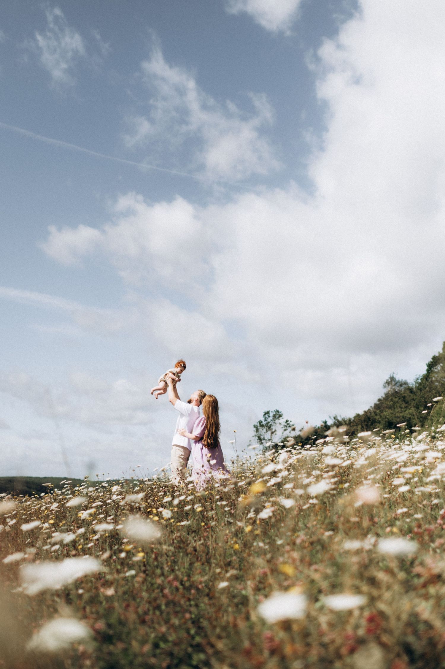 parents lifting baby up in a wildflower field, Kent family photographer
