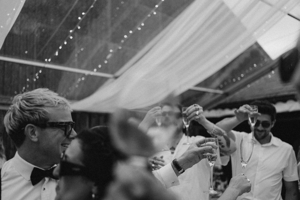 Guests laughing and celebrating at a Cotswolds wedding, editorial photography