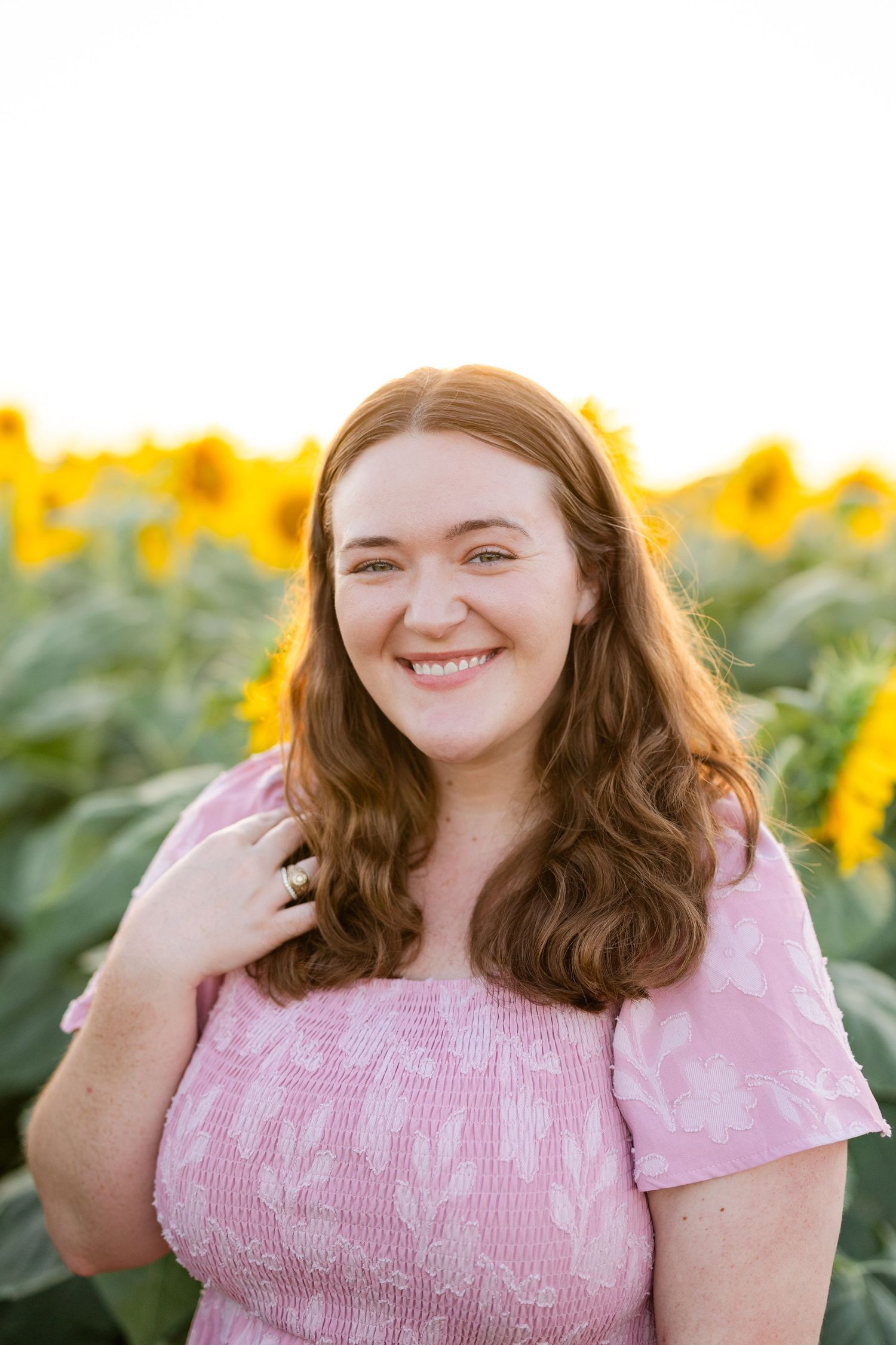 Portrait in sunflower field at sunset with blue dress and natural smile.