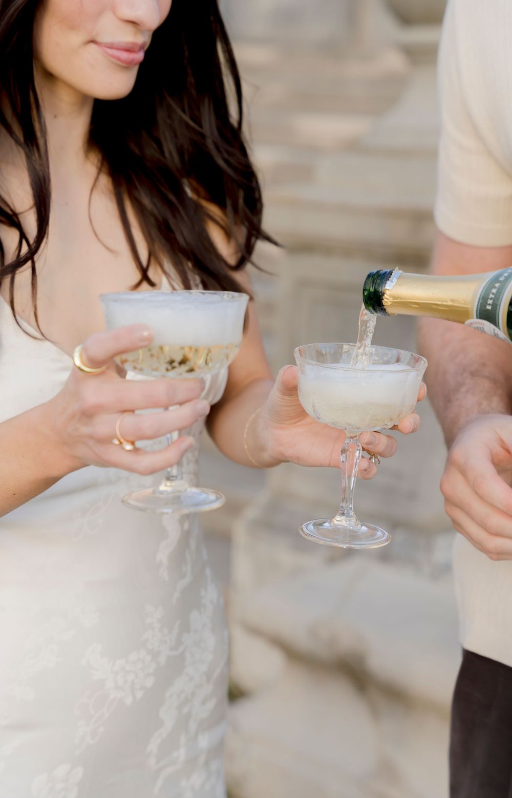 People holding elegant cocktail glasses with frothy white drinks at an elegant event.