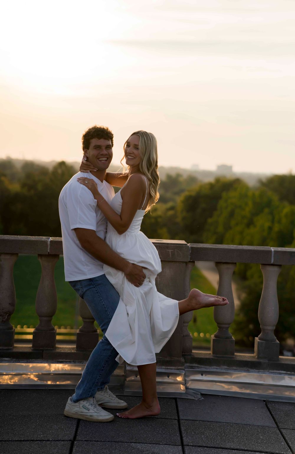 Romantic sunset portrait of a couple embracing on a terrace with scenic views.