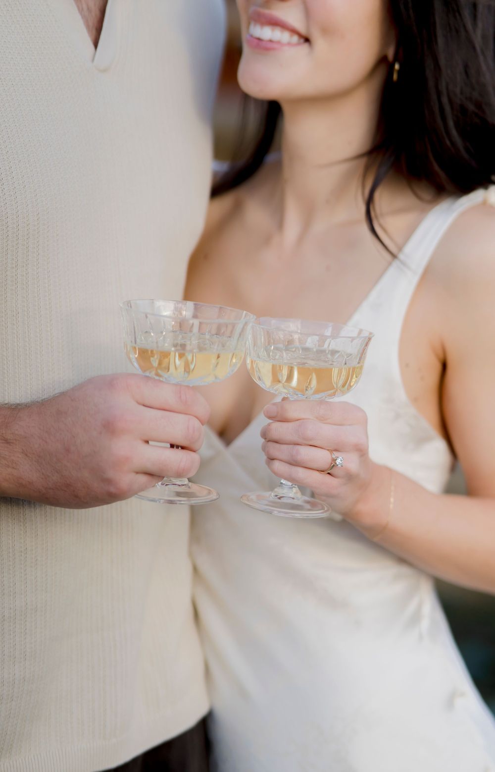 Two champagne glasses clink together in celebration against a soft blurred background.