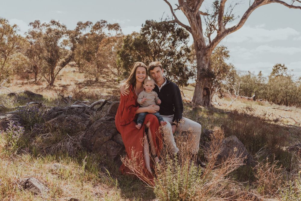 A family sits together on rocky terrain surrounded by eucalyptus trees.