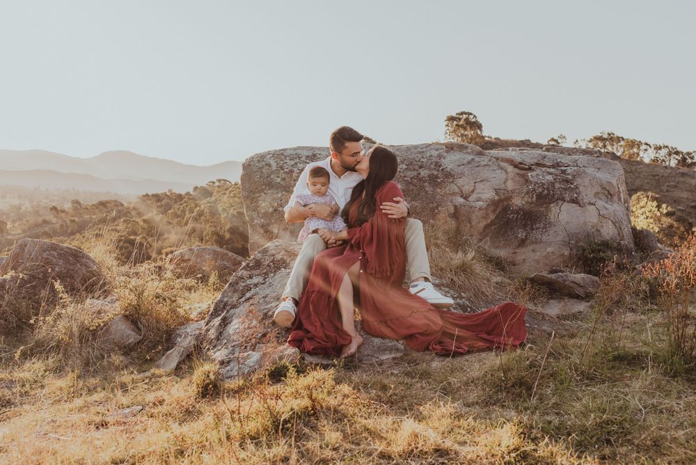 Family sitting on rocky outcrop during golden hour in natural setting.