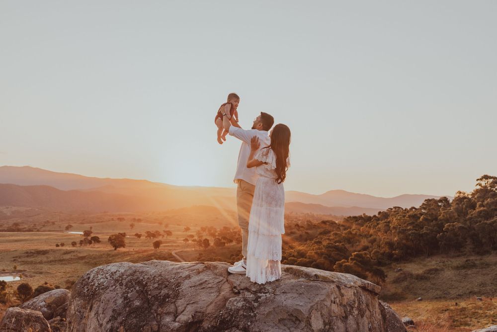 Two figures stand on a rocky outcrop silhouetted against a stunning sunset.