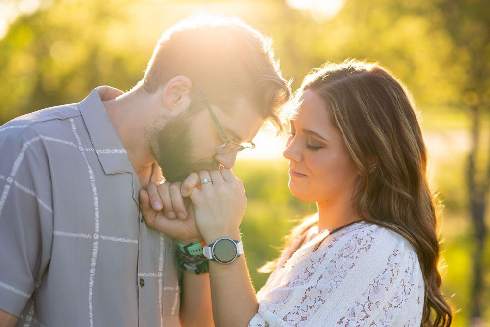 Okobjoi and Sioux City engagement photographer photo of a man kissing the ring finger of a female during golden hour sun light.