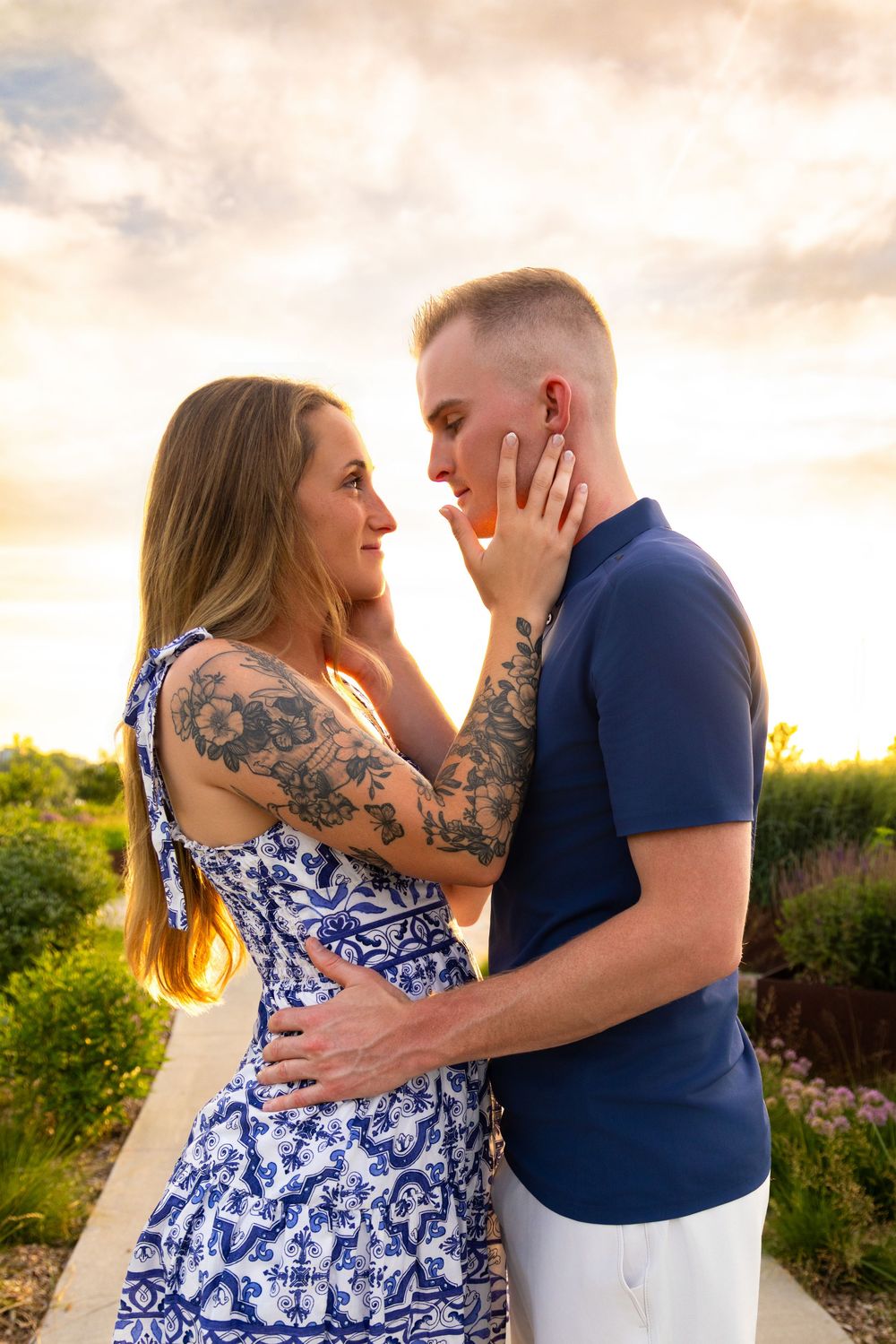 Emotional engagement photo of a couple staring into each other's eyes while the sunset sky is prominent in the background.