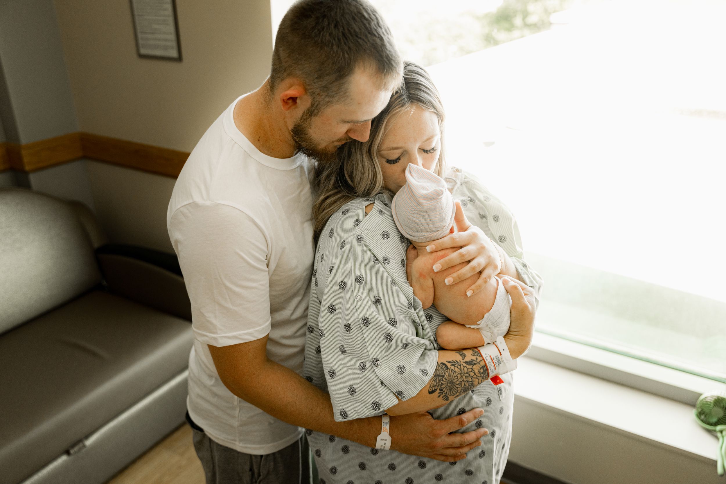 Family holding new baby in Fort Wayne Parkview hospital newborn session wearing neutrals.