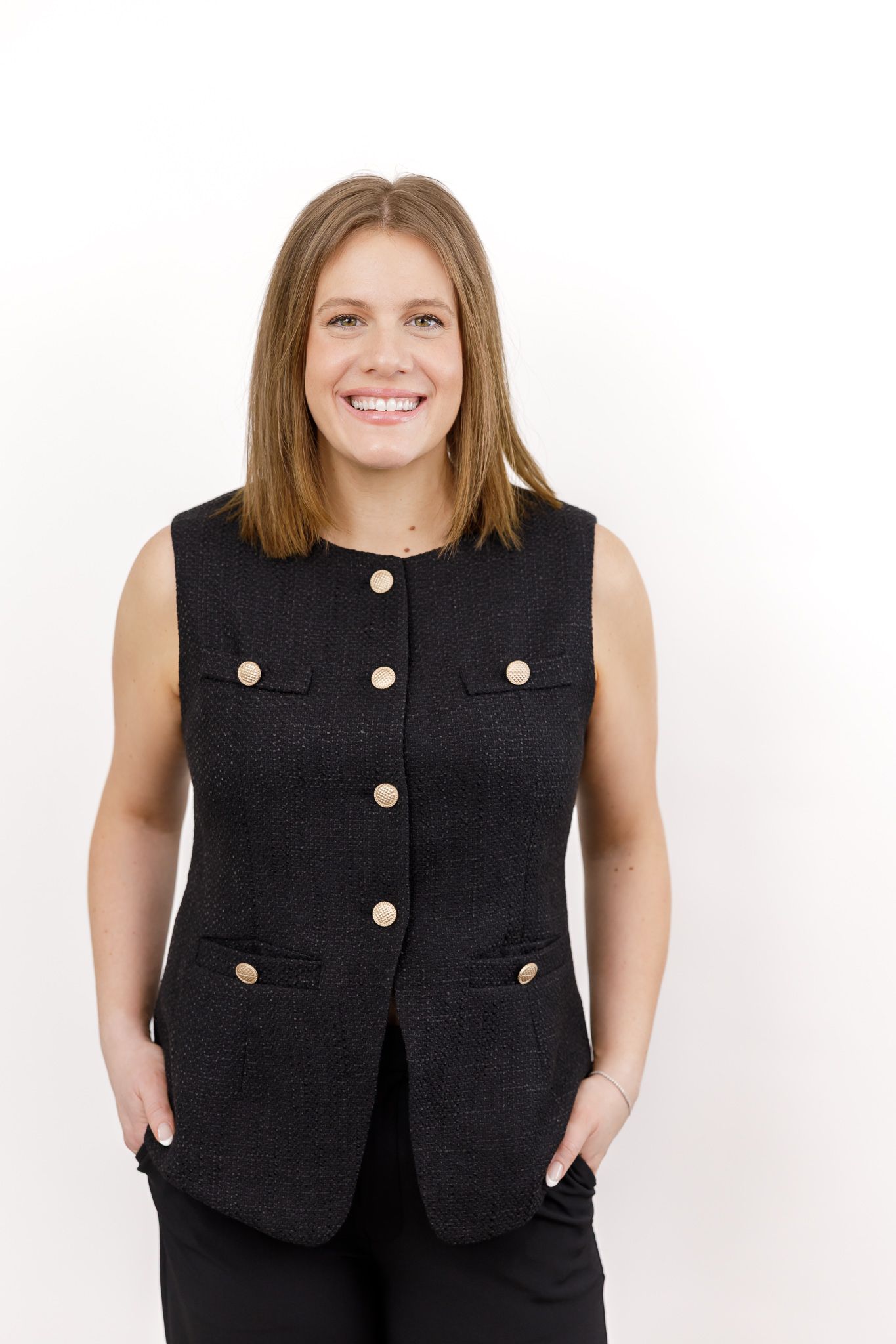 female real estate agent headshot in Auburn, WA against white backdrop wearing black sleeveless suit  smiling at camera