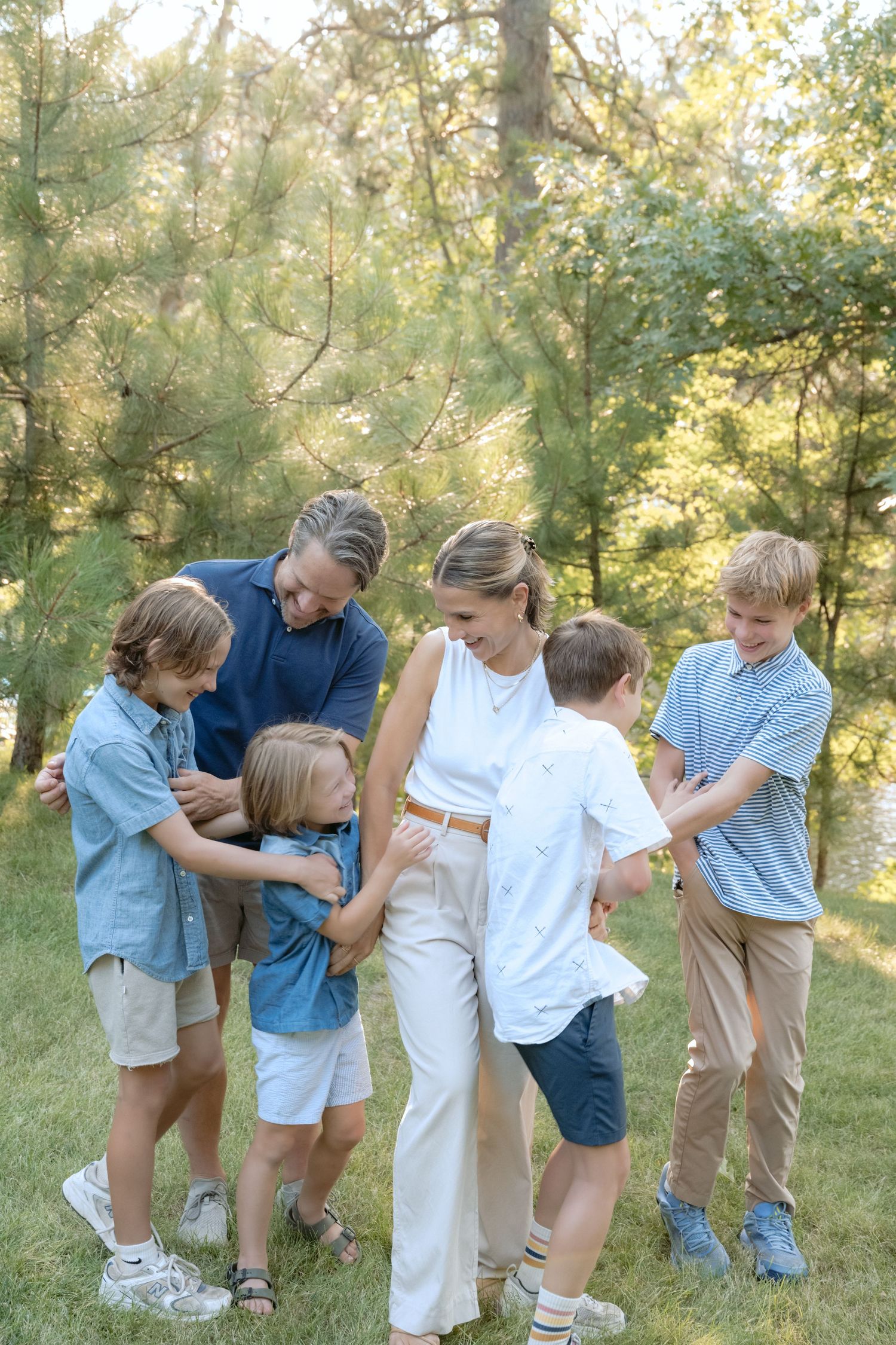Parents and their four boys tickle and laugh during an outdoor family session in Holcombe, WI.