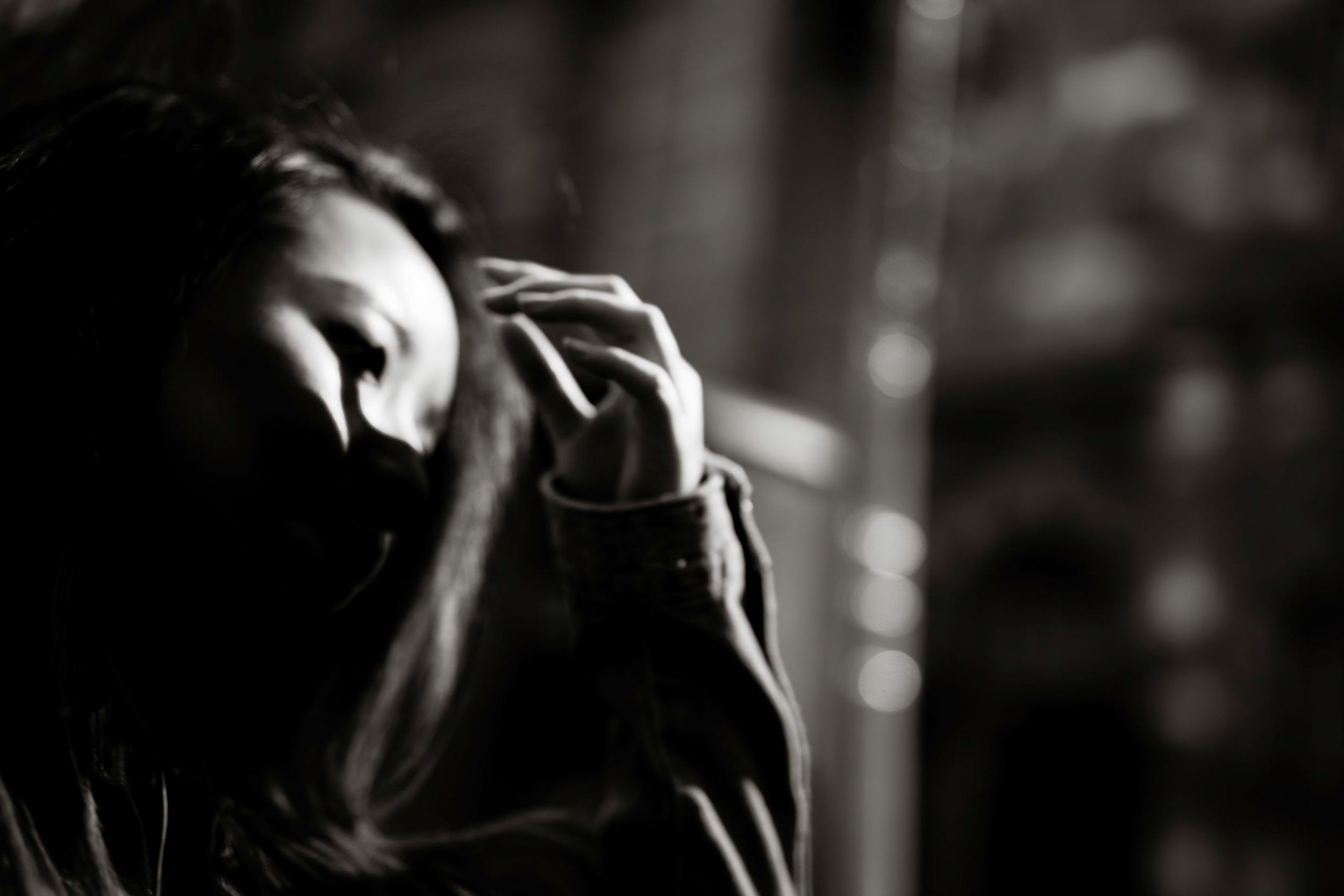 Black and white photo of a woman with her hand raised to her face in a pensive, emotional pose.