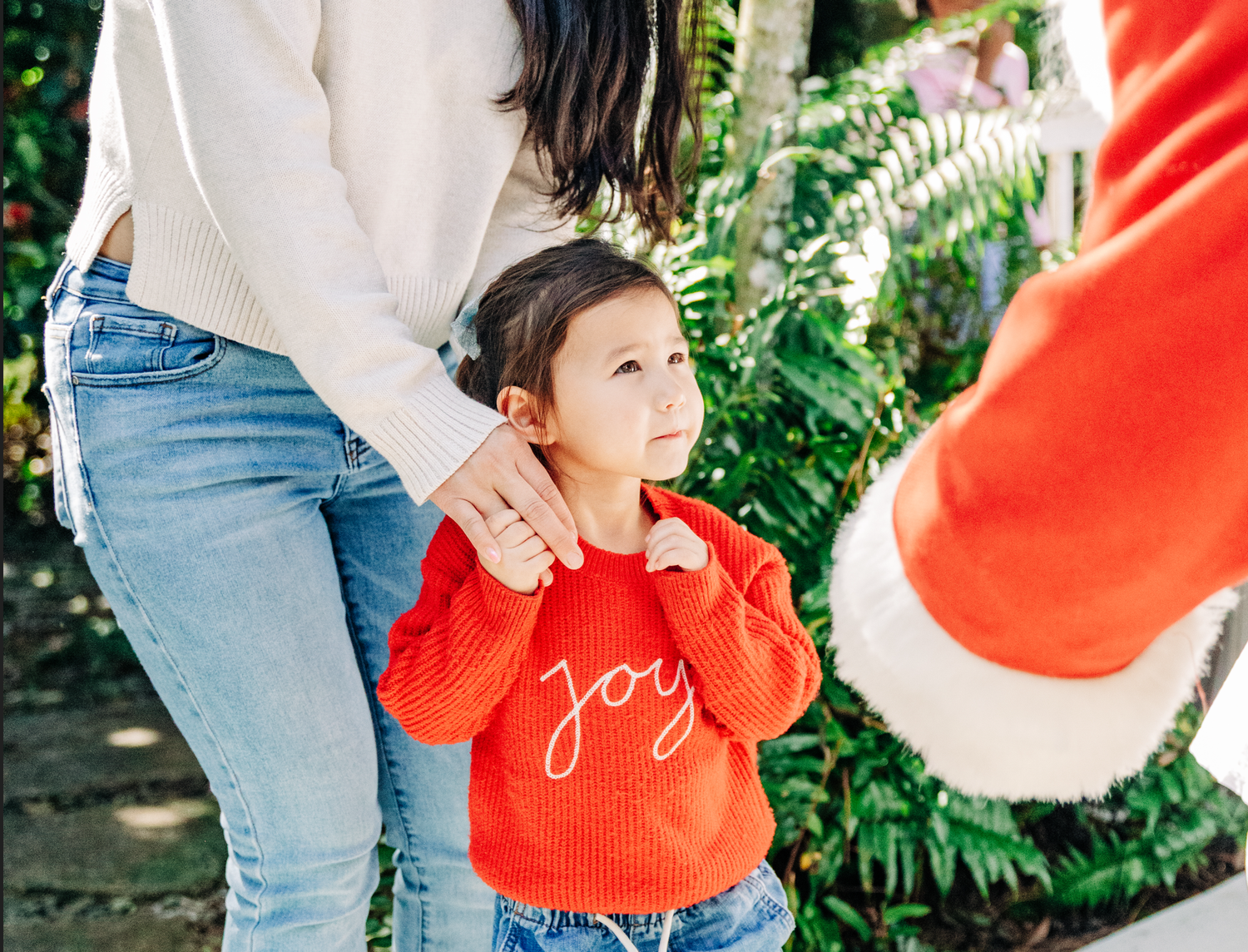 Lake Worth Beach Santa photos of a young child meeting Santa Claus while holding her mother’s hand.