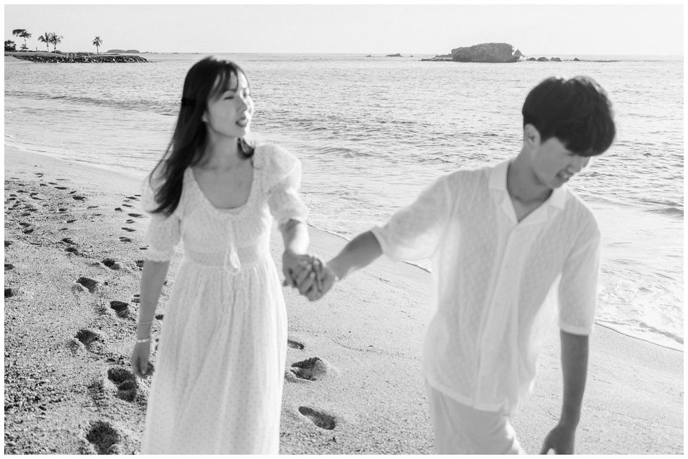 Punta Mita Family Photographer documenting a mother and son walking hand in hand through the ocean waves on a sunny beach.