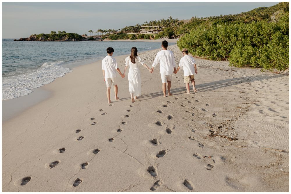 Family Photo Session along the sandy beach, with everyone walking together and leaving footprints by the ocean.