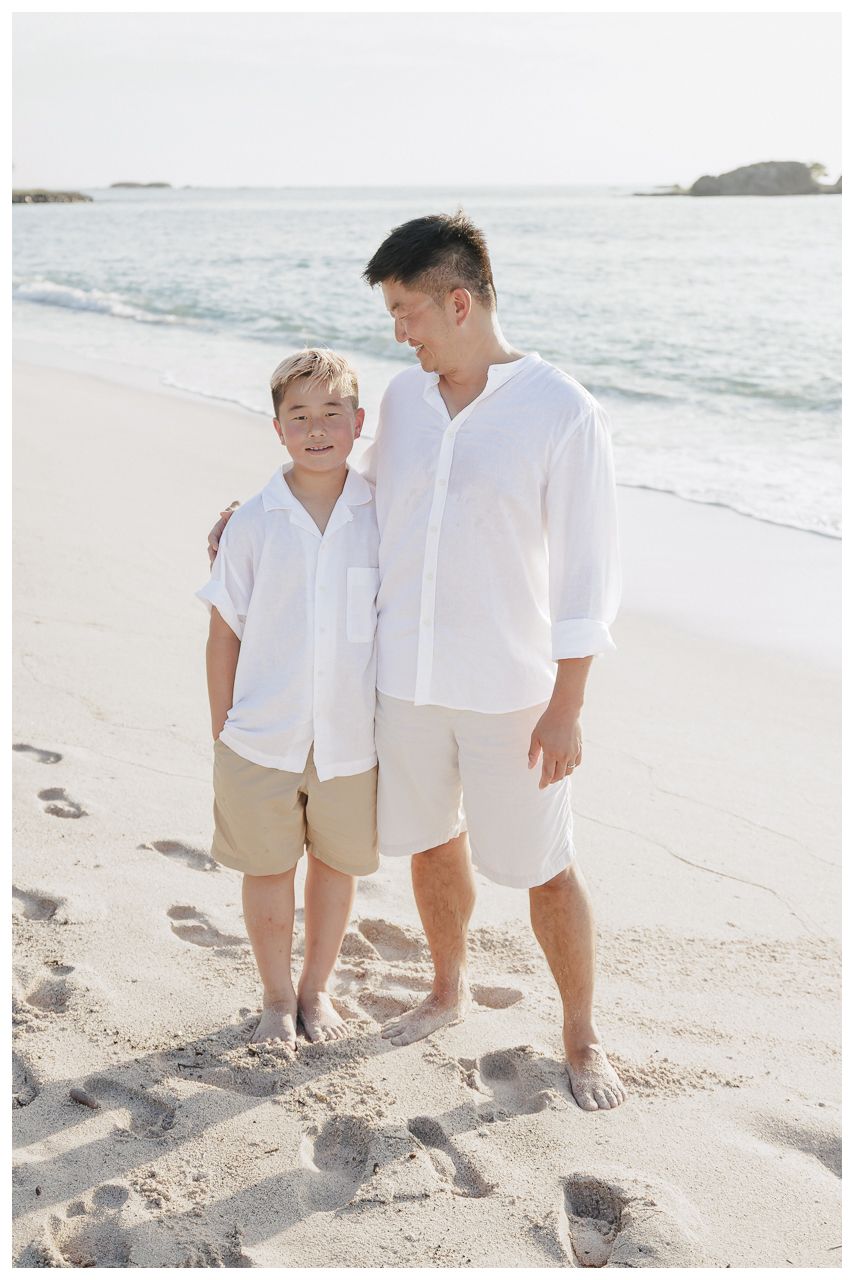 Punta Mita Family Photographer capturing a father and son smiling together on a sunny beach by the ocean.