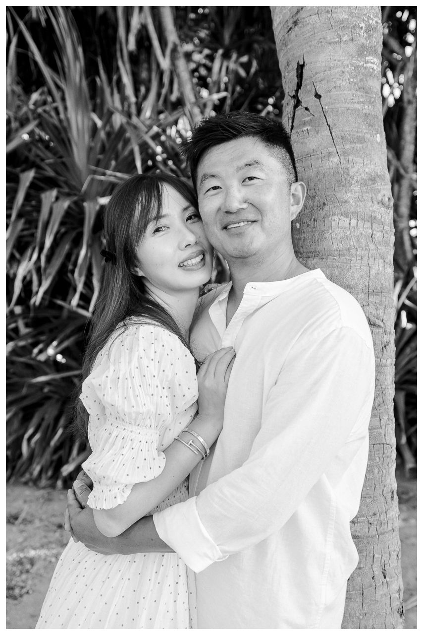 St. Regis Punta Mita Photographer documenting a couple embracing beneath a palm tree surrounded by tropical greenery.