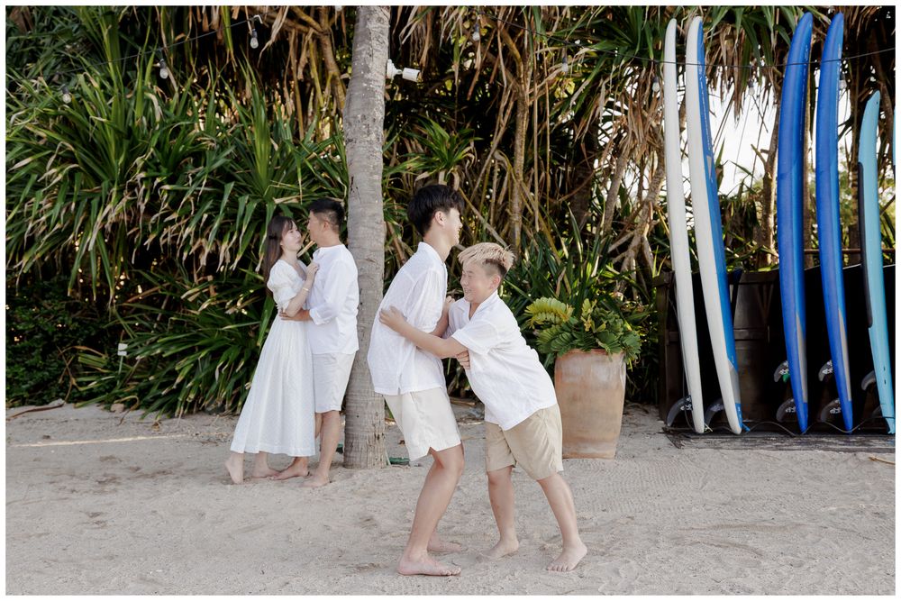 Punta Mita Family Photographer capturing a joyful beach moment with tropical palms and colorful surfboards in the background.