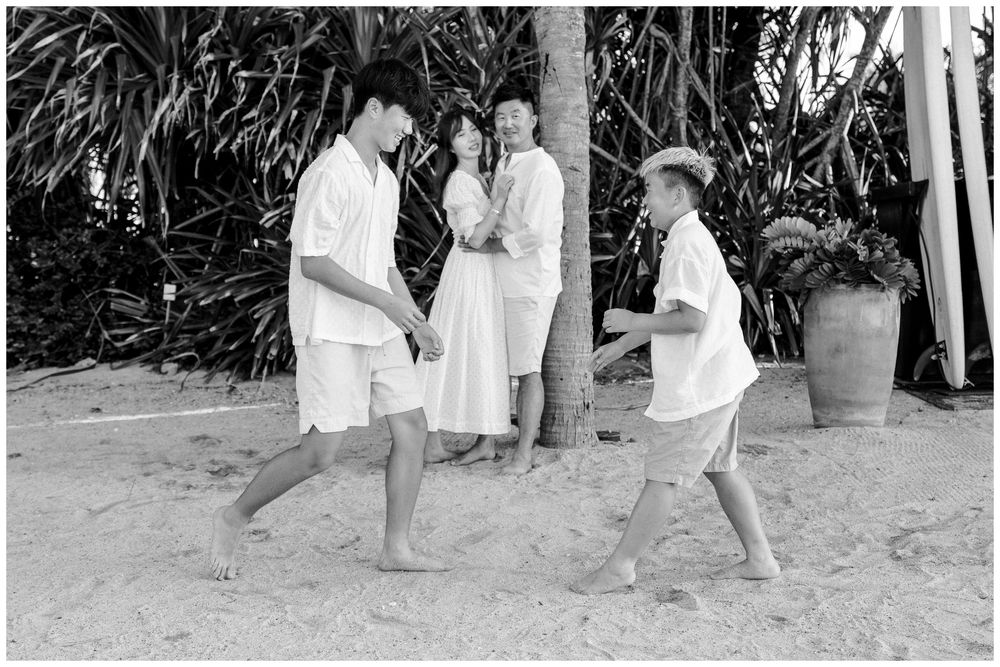 Family Photo Session at The St. Regis Punta Mita, with two boys playing in the sand as their parents watch nearby.
