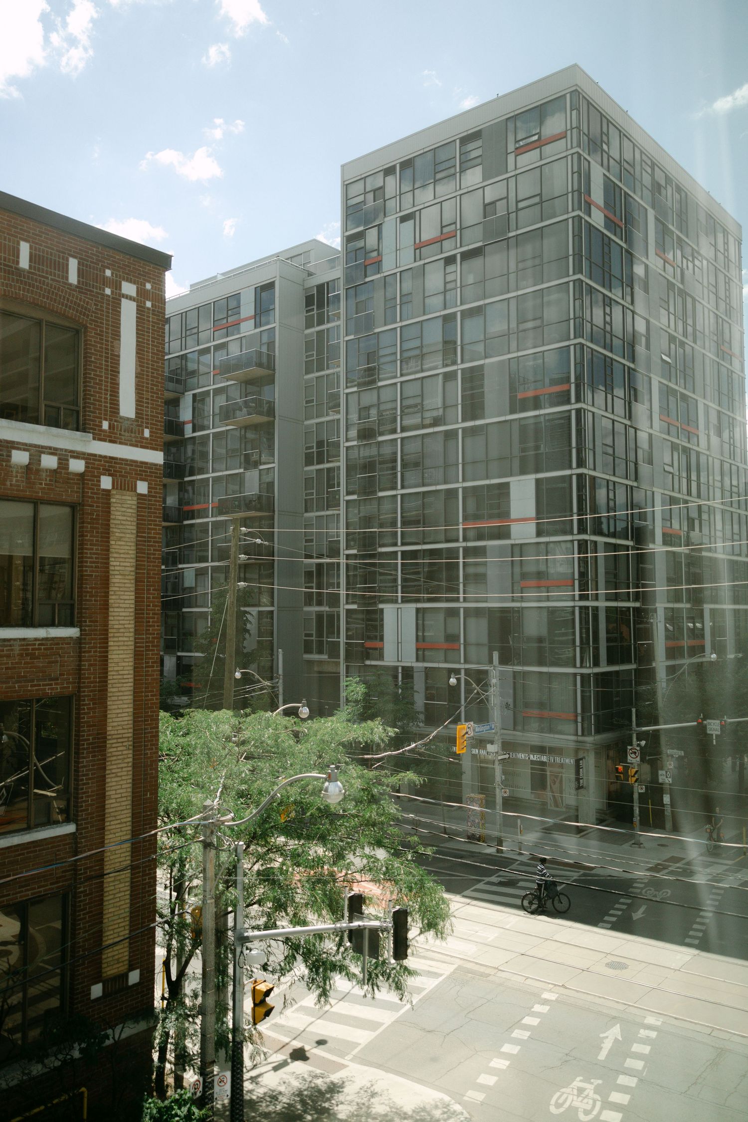 Urban street view through glass window showing modern glass office building and brick building intersection.