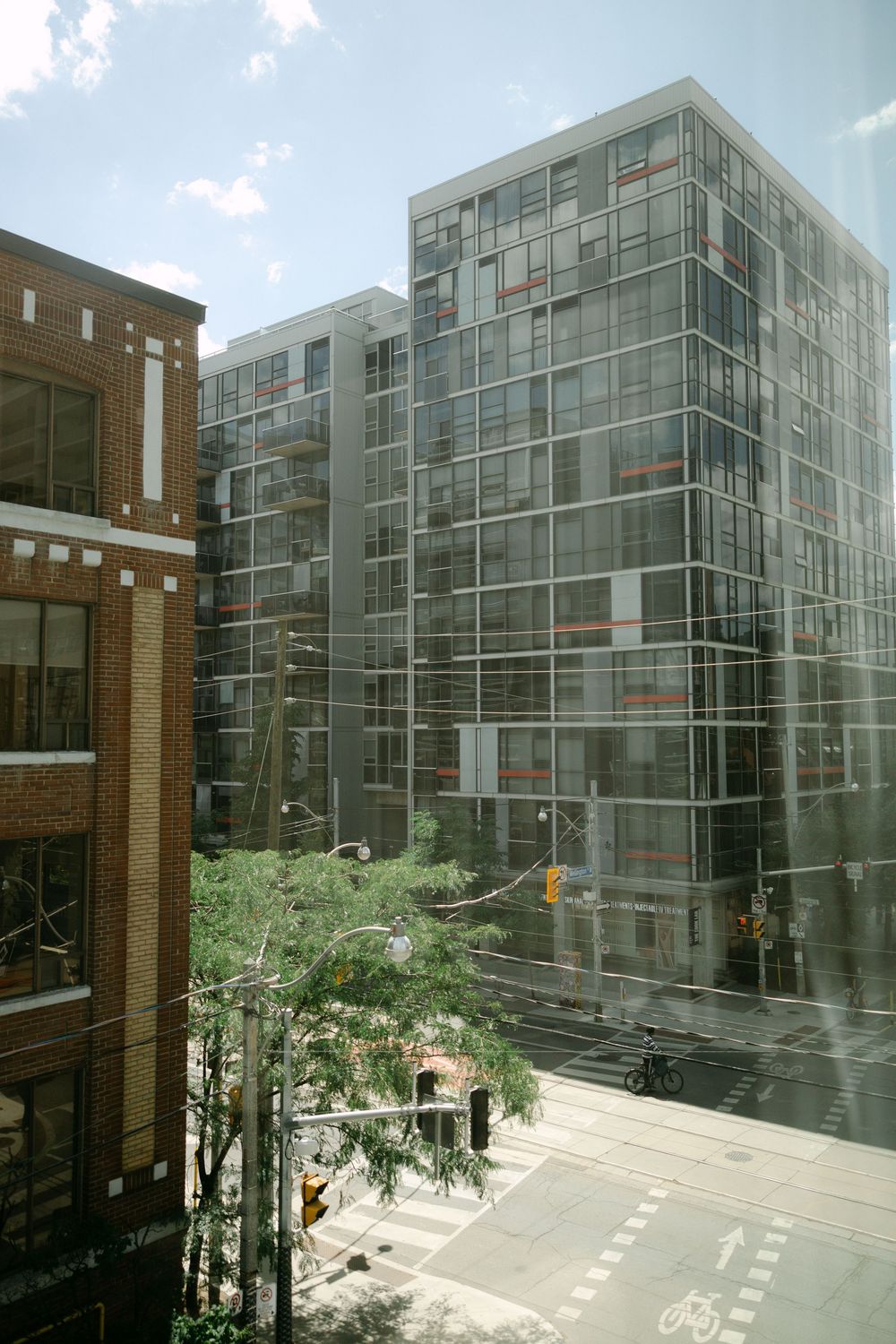 Urban street view through glass window showing modern glass office building and brick building intersection.