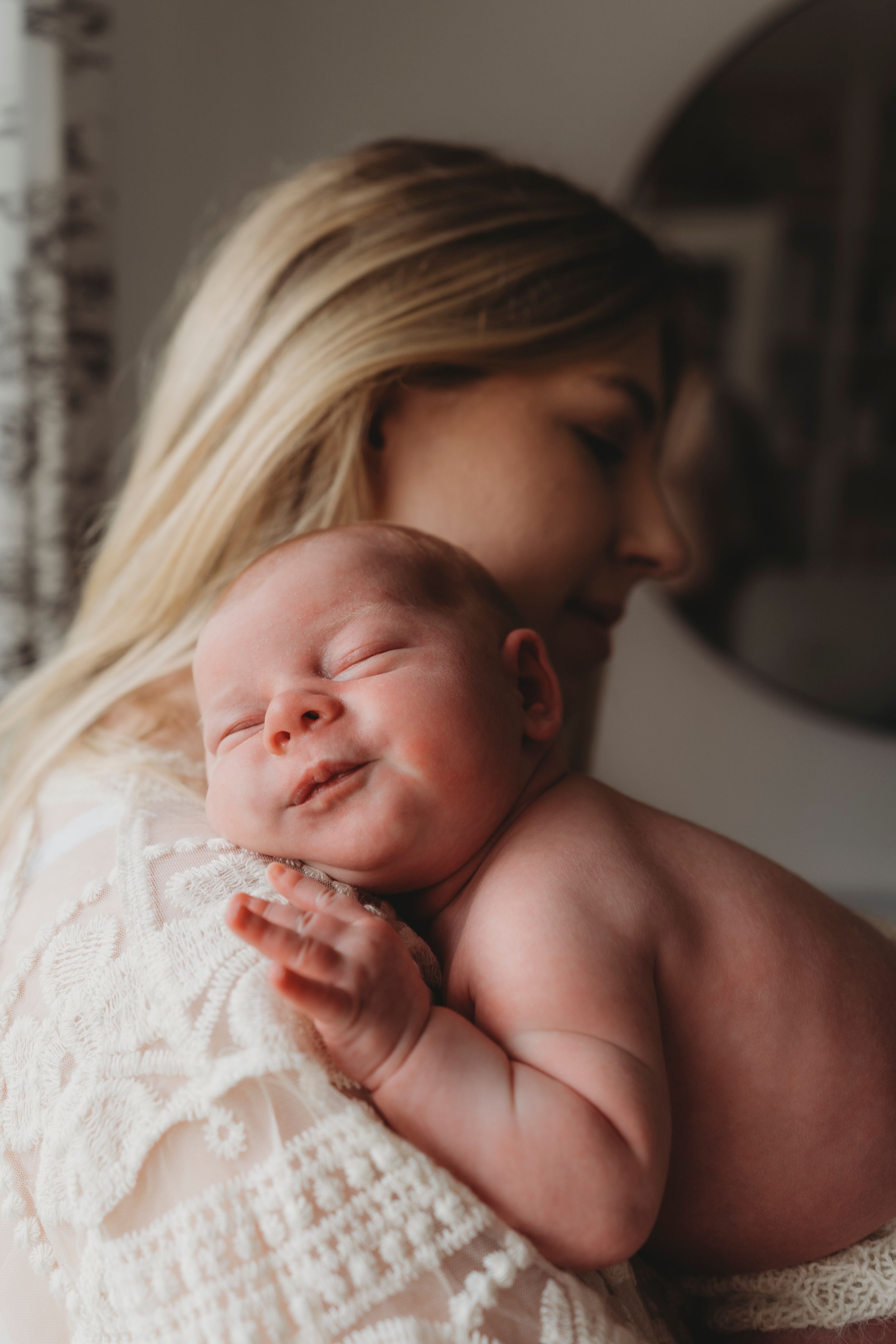 An intimate portrait of a newborn baby nestled against white lace, peacefully sleeping.