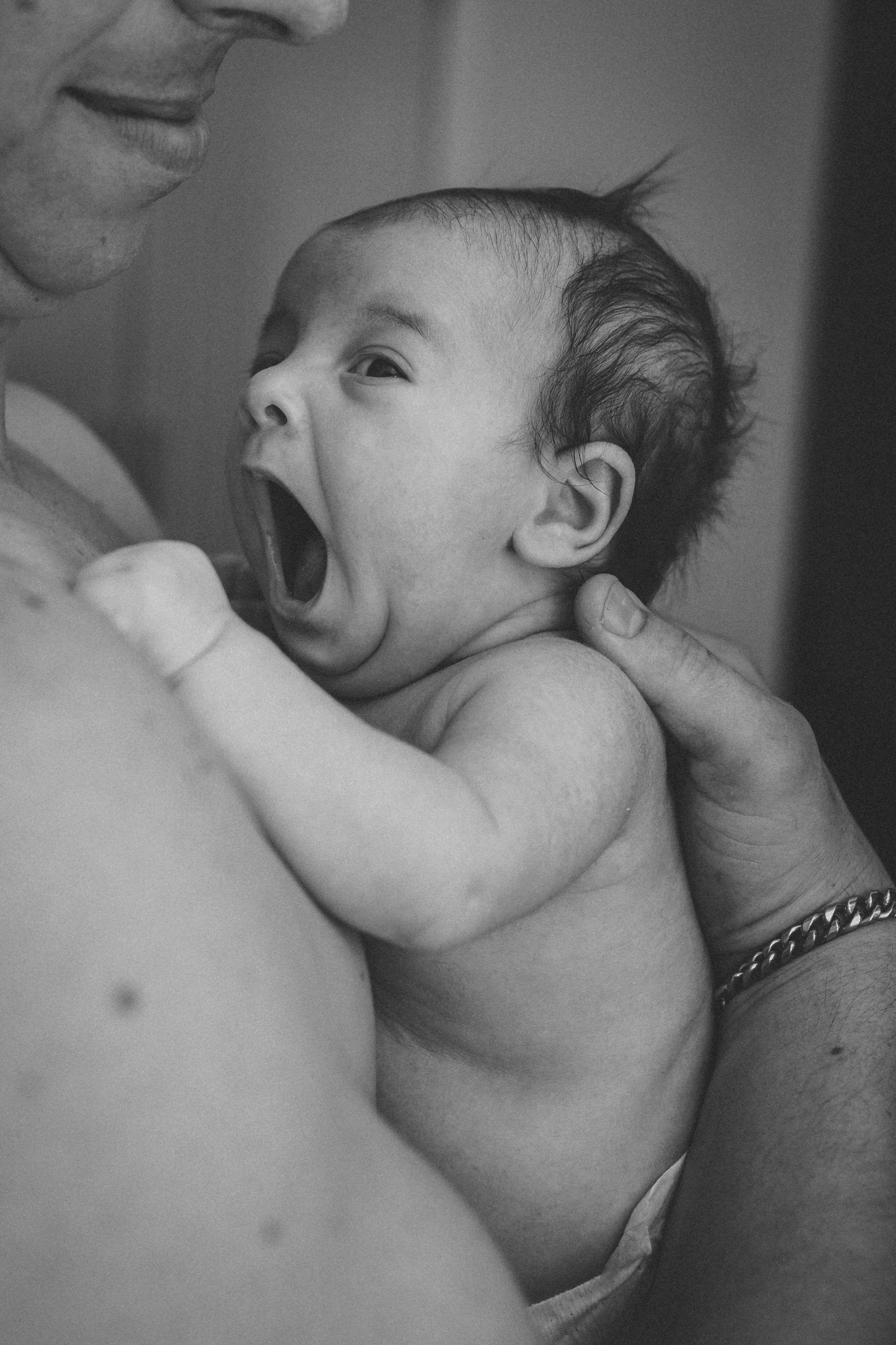 Black and white photograph of an expressive baby yawning or laughing.