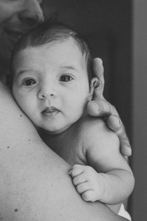 Intimate black and white close-up of a baby resting against a shoulder.