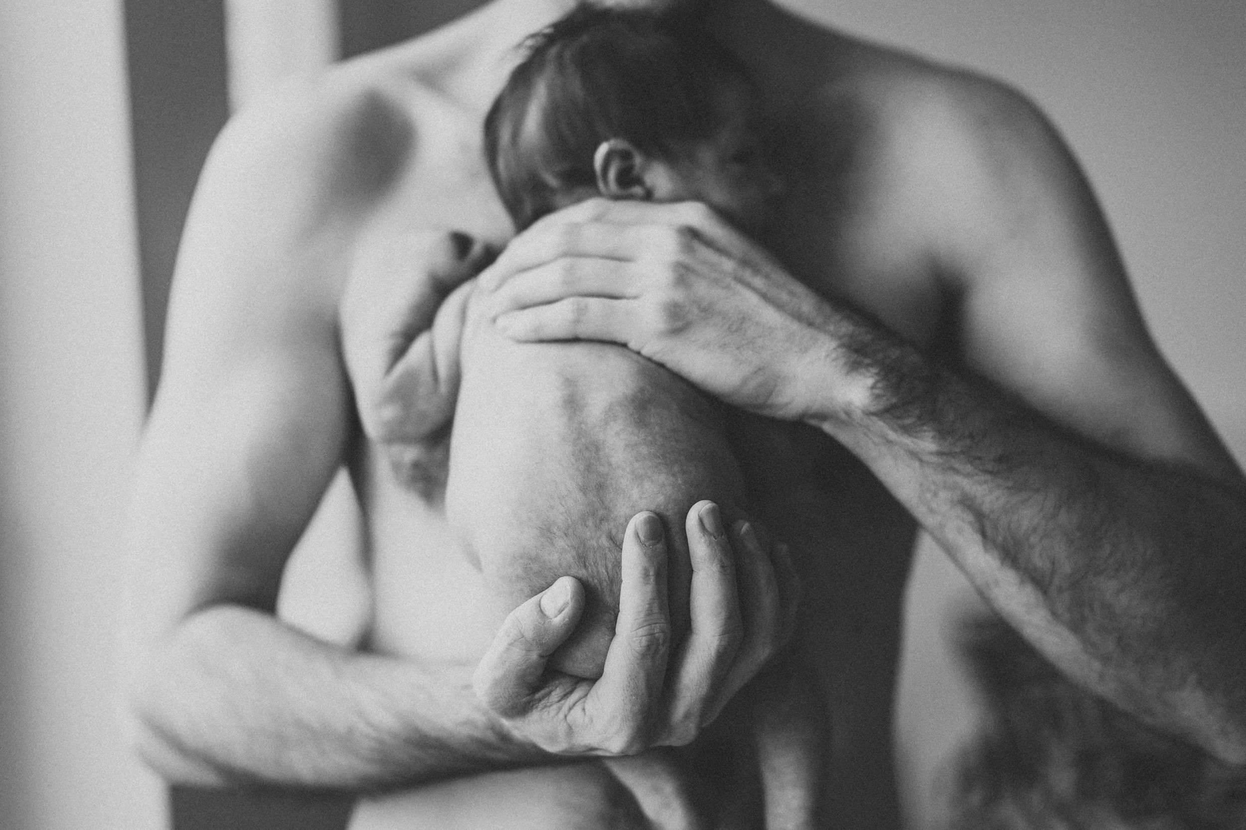 Artistic black and white photograph of hands touching bare skin.