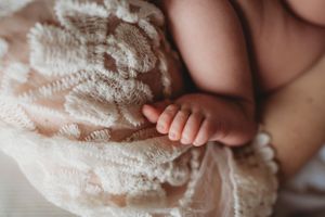 Delicate detail of a baby's tiny feet against white lace fabric.