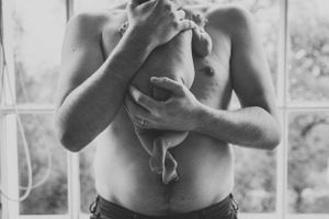 Monochrome image showing tender moment of nurturing and feeding near window.