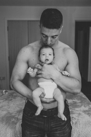 Black and white portrait showing tender moment between parent and baby.