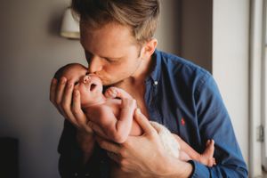 Tender moment of affection between a parent and newborn in gentle natural light.