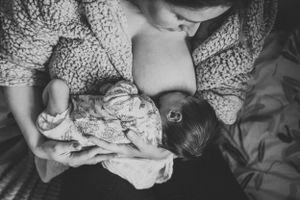 A black and white overhead view of a tender nursing moment between parent and infant.